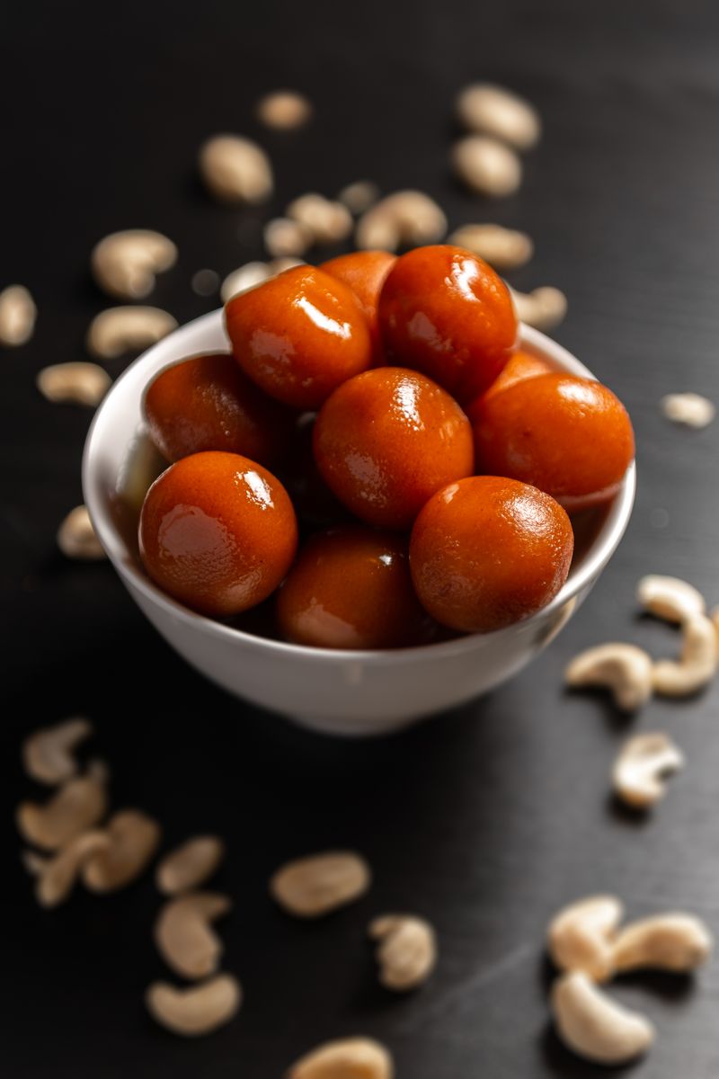 Gulab jamun soaking in syrup, scattered with cashew.